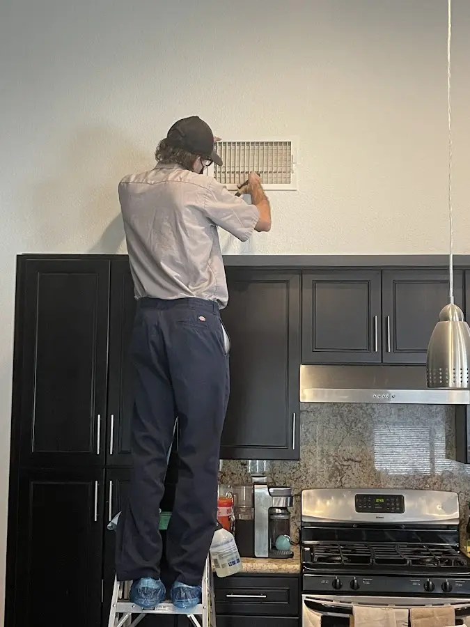 Technician inspecting an air vent during HVAC service in River Oaks